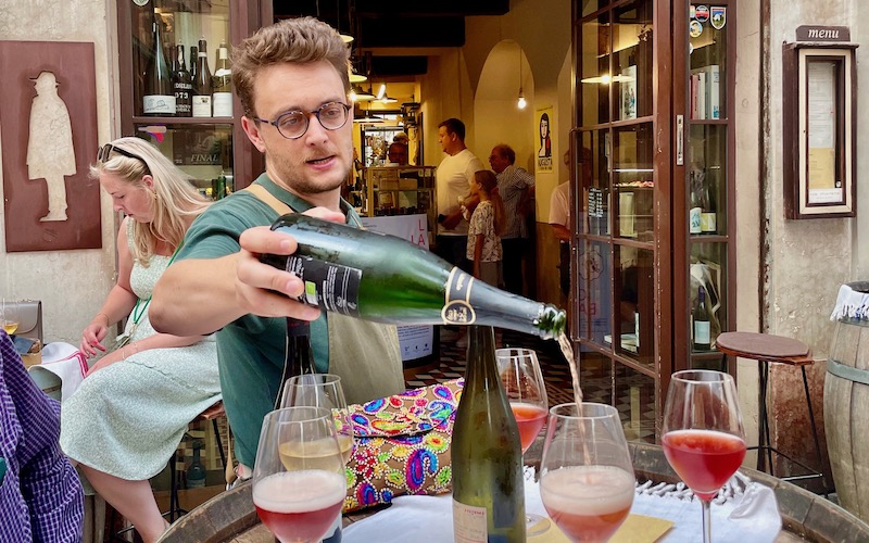 Man pouring sparkling pink wine outside Tabarro wine bar - Parma Food Tour