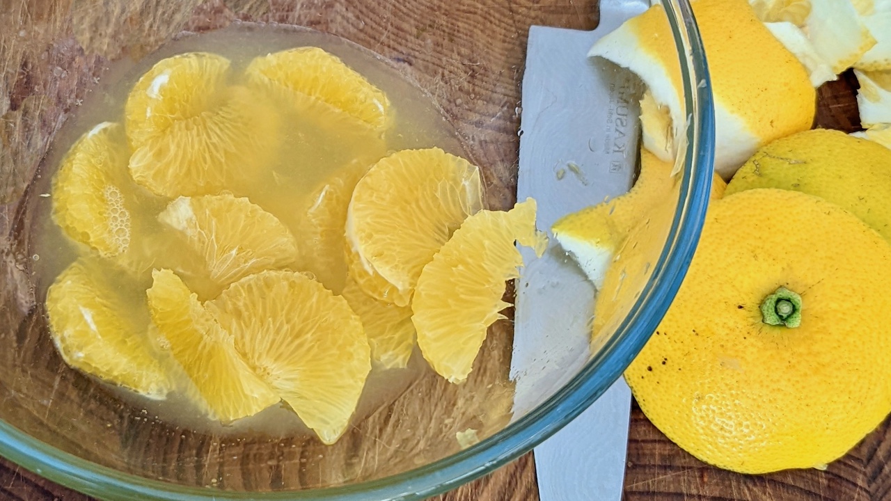 How To Segment Citrus (Orange segments in a bowl with knife and peel beside)