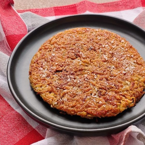 Rösti (Roesti - Swiss Potato Cake) on a black plate with checked tablecloth