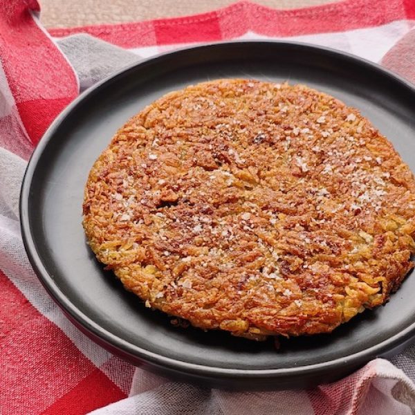Rösti (Swiss Potato Cake) Rösti (Roesti - Swiss Potato Cake) on a black plate with checked tablecloth